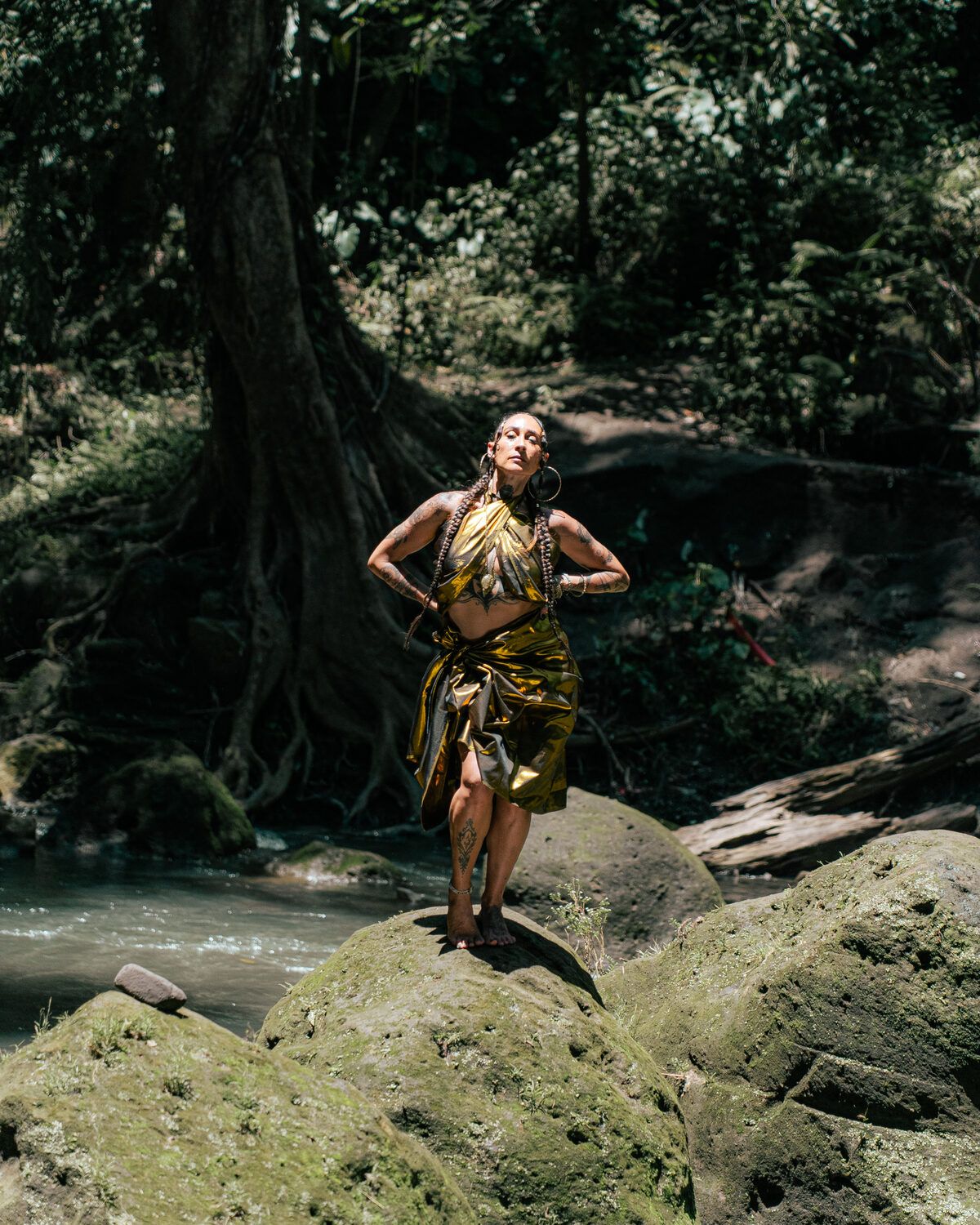 TIHANE in gold standing on a forest rock